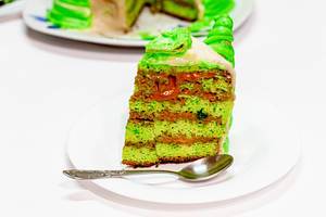 Slice of homemade green cake on a platter with a spoon (Flip 2019)