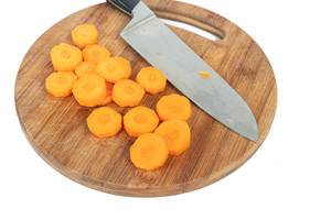 Sliced Carrot on the round wooden board with knife