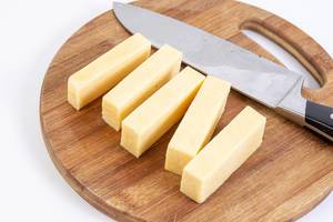 Sliced Cheddar Cheese on the kitchen wooden board