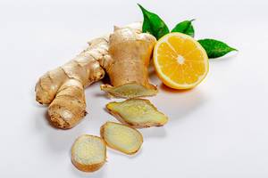 Sliced fresh ginger with lemon and green leaves