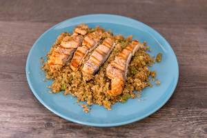 sliced, fried salmon with couscous on wooden table