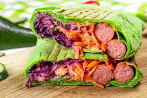 Sliced green pita bread with vegetables and smoked sausages (Flip 2020)