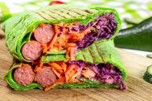 Sliced green pita bread with vegetables and smoked sausages