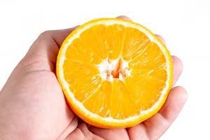Sliced Half Orange fruit in the hand above white background