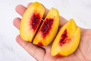 Sliced Peach in the hand above white background (Flip 2019)