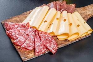 Sliced salami, ham, jerky and cheese on an old wooden kitchen Board