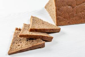 Sliced triangular pieces of black bread on a white table