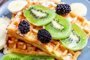 Slices of kiwi and banana with mulberry on Belgian waffles close-up (Flip 2019)
