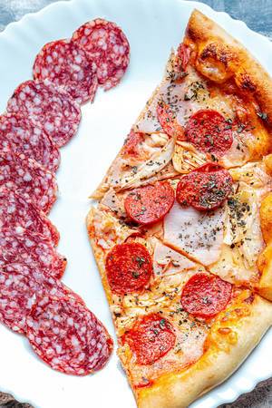 Slices of meat pizza with sliced smoked sausage on a white plate (Flip 2019) (Flip 2019)