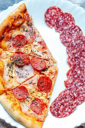Slices-of-meat-pizza-with-sliced-smoked-sausage-on-a-white-plate.jpg