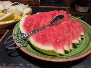 Slices of watermelon o a plate with tongs for serving