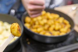 Small spicy fried potato balls are being made in an open kitchen at Fibo Cologne