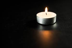 Small white candle on a black surface