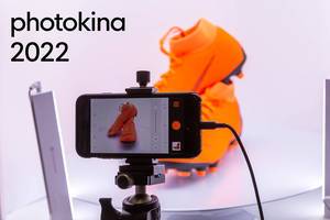 Smartphone auf einem Stativ, mit geöffneter Fotoapparat für Produktfotografie und dem Bildtitel "photokina 2022"