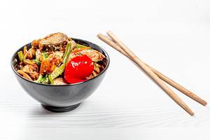 Soba noodles with tuna, asparagus, pepper and mushrooms in sweet and sour sauce in black bowl with chopsticks on white wooden background