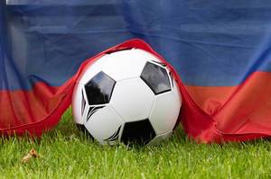 Soccer ball on grass covered with Russian flag