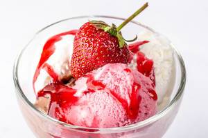 Sommerlicher Eisbecher mit verschiedenen Eiskugeln, süßer Erdbeersauce und mit einer Erdbeere verziert