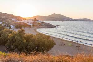 Sonnenuntergang über Paros taucht Strand und typische griechische Bauten in goldenes Licht