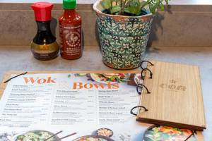 Soy sauce, hot chili sauce, mint and the menu of the coa Wok & Bowl restaurant with wooden design