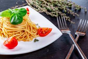 Spaghetti with forks, tomatoes and rosemary