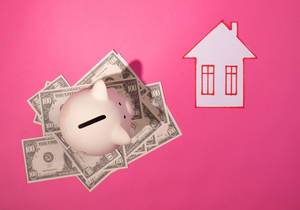 Sparschwein steht auf amerikanischen Geldscheinen, neben einem Haus aus Papier, vor pinke Hintergrund