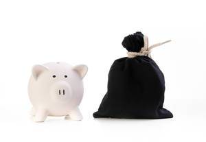 Sparschwein und schwarzer Geldsack vor weißem Hintergrund