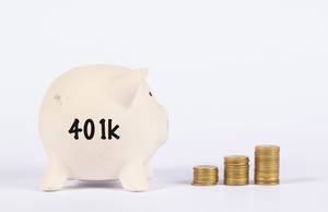 Sparschwein von der Seite mit der Aufschrift "401k" und neben einer Treppe aus gestapelten Münzen