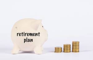 Sparschwein von der Seite mit der Aufschrift "Plan für den Ruhestand" und neben einer Treppe aus gestapelten Münzen