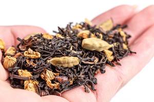 Spiced dry black tea with spices on hand, close-up