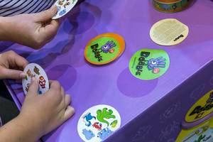 SPIEL 19 gaming fair in Essen: the hands of two visitors playing visual perception game "Dobble" with animal symbols on round cards