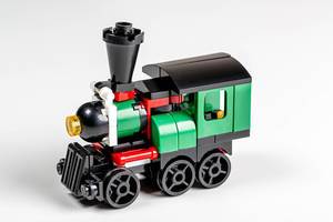 Spielzeug aus Plastik: grüne Lokomotive vor weißem Hintergrund