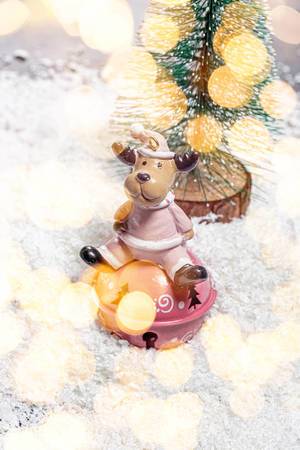 Spielzeug Rentier auf weißem Schnee mit Weihnachtsbaum und bokeh Hintergrund