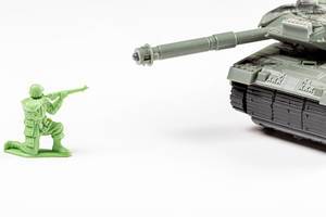 Spielzeug Soldat richtet eine Waffe gegen einen Panzer - Konzept von Krieg