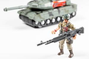 Spielzeug Soldaten mit Waffen in den Händen und einem Panzer im Hintergrund