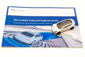 Spielzeugauto auf der Infrobroschüre des Verkehrsministerium "Mobile Zukunft beginnt jetzt!" - revolutionierter Verkehr durch autonomes Fahren