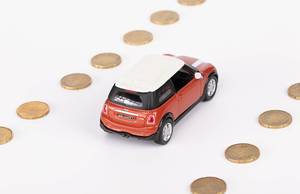 Spielzeugauto fährt auf einer Straße aus Münzen gemacht