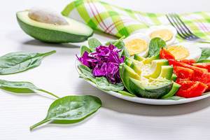 Spinatblätter, Blaukraut, geschnittenes Gemüse und Frühstückseier
