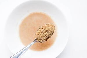 Spoon of ground flaxseed meal and flax egg on white background