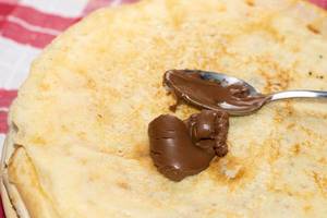 Spoon with chocolate cream on the pancakes