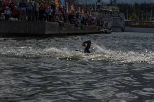 Sportathlet kurz vor dem Zielleinlauf für den Schwimmwettkampf beim Ironman 70.3., mit Zuschauern an der Küste von Lahti, Finnland