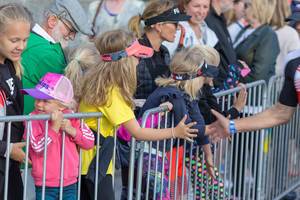 Sportbegeisterte Zuschauer und Kinder hinter der Sicherheitsabsperrung beim Abklatschen mit den Ironman-Teilnehmern, auf der Marathonstrecke
