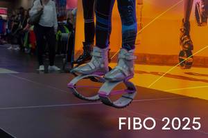 Sportmesse-Besucher testen Kargo Jumps mit futuristischen Hüpfschuhen für das Fitnesstraining, neben dem Bildtitel "Fibo 2025"