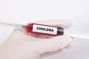 Spritze mit Injektionsnadel und dem Text Cholera
