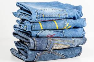 Stack of various shades of blue jeans on white background