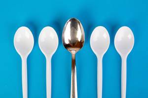 Stainless steel and plastic spoons on blue background