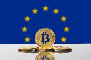 Stehender goldener Bitcoin eingefasst von den Sternen auf der Flagge der Europäischen Union (EU)