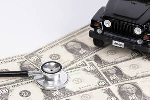 Stethoscope and black car on dollar banknotes
