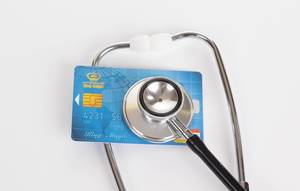 Stethoscope and Visa credit card on white background