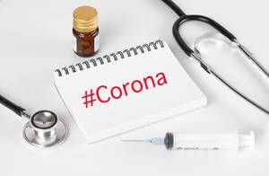 Stethoscope with notebook and syrige and #Corona text