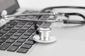Stethoskop auf einem Laptop als Symbolbild für die Online-Sprechstunde über den Computer, als Alternative zum regulären Arztbesuch